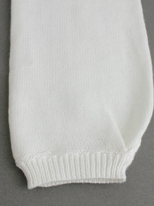 Detailed macro shot of fine knit texture and ribbed cuff design on white sweater