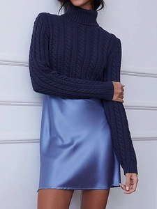Detail of navy cable knit turtleneck sweater paired with a light blue satin slip dress