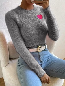 Detail of grey crewneck knit sweater featuring a vibrant pink heart patch on the chest