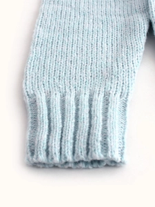 Close-up of light blue knit sweater cuff showing detailed ribbed texture and stitching