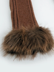 Detail eines dunkelbraunen Rippstrick-Ärmels mit luxuriösem Kunstpelzbesatz für den Winter