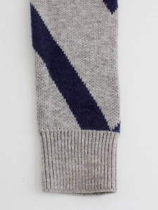 Close-up of ribbed knit sweater cuffs with navy blue diagonal stripes on gray wool blend