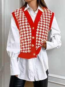 Dettaglio del gilet in maglia pied de poule rosso con bottoni dorati su camicia bianca