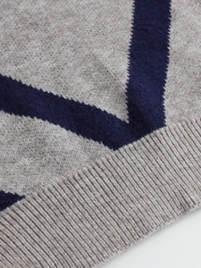 Detailed macro view of the grey ribbed knit sweater with navy blue geometric V-pattern