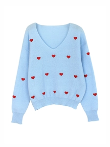 Dettaglio maglione in maglia azzurro con scollo a V, ricamo a cuori e polsini a costine