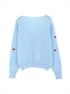 Dettaglio del maglione in maglia azzurro con cuori rossi e polsini delle maniche a coste