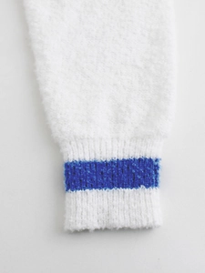 Detailed close-up of ribbed cuffs on a white plush knit sweater with a blue stripe accent