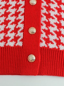 Dettaglio gilet in maglia pied-de-poule bianco e rosso con bottoni dorati