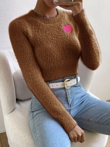 Detail showing plush brown knit sweater texture and pink heart patch with long sleeves