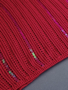Close-up of red V-neck hollow knit sweater featuring shimmering sequins and intricate crochet
