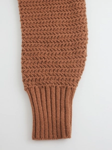 Macro shot of brown knit sweater cuff featuring herringbone pattern and ribbed detailing