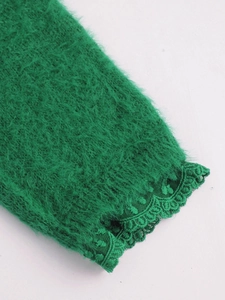Détail de la manche d'un pull en maille vert émeraude avec des poignets en dentelle fine