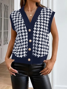 Dettaglio del gilet in maglia con scollo a V, motivo pied de poule e bottoni d'oro