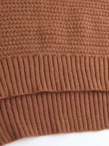 Close-up of warm camel knit sweater showing mixed textures and ribbed hem details