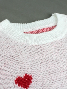 Women's white knitted ribbed sweater featuring red heart patterns and round neckline