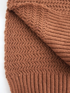 Detail of caramel brown knit sweater featuring wavy texture and ribbed hem craftsmanship
