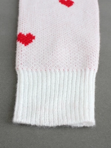 Close-up of white ribbed knit sleeve with red heart pattern and elastic cuff detail