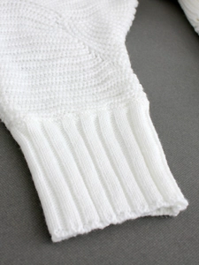 White knit sweater dress featuring long sleeves with ribbed cuffs and unique texture
