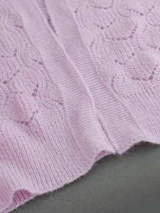 Détail du cardigan tricoté lilas avec motif ajouré et texture de maille torsadée