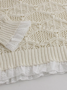 Beige knit sweater with intricate cutout patterns and white floral lace cuffs