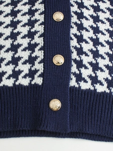 Dettaglio del gilet in maglia pied-de-poule blu e bianco con bottoni dorati a rilievo
