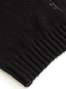 Close-up of black V-neck knit sweater featuring ribbed cuffs and wool blend texture