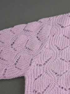Détail du cardigan en maille ajourée rose clair avec une texture douce en mohair