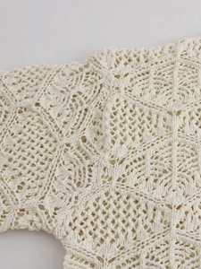 Detailed macro view of beige crochet knit sweater with floral hollow patterns