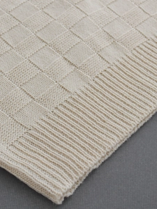 Pull sans manches en maille gaufrée beige avec bordure côtelée sur fond minimaliste