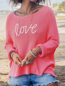 Detail of pink knitted long sleeve sweater with white love lettering on the beach