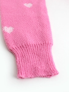 Close-up of pink knit fabric with white heart pattern and ribbed cuff detail