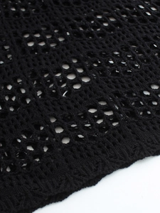 Close-up detail of black crochet knit fabric showing textured hollow out honeycomb pattern