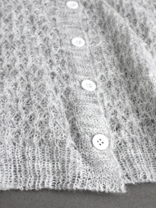 Nahaufnahme der flauschigen hellgrauen Strickjacke mit Details aus weißen Kunstharzknöpfen