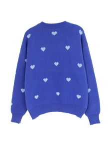 Detail of the blue knitted sweater featuring white heart patterns and ribbed texture cuff