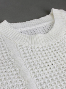 Detailed close-up of white knit sweater featuring honeycomb texture and ribbed neckline