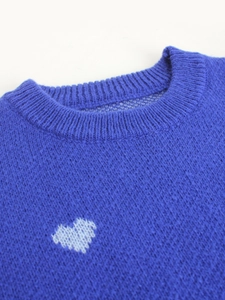 Detailed close-up of ribbed crewneck and white heart patterns on blue knit sweater