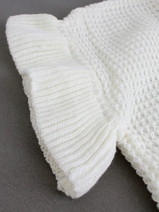 Close-up of white rib-knit texture and soft fabric detail on a short sleeve sweater