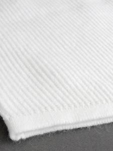 Close-up of white ribbed knit vest sweater showing high-quality textured fabric detail