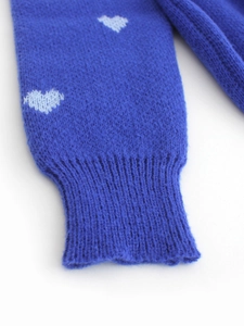 Detail of ribbed cuff with heart pattern on plush navy blue knit sweater sleeve