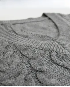 Detail of grey cable knit vest showing V-neckline texture and high-quality weave