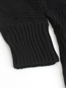 Detail shot of the ribbed cuff on a black knitted sweater with soft thick texture