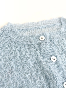 Detailansicht der hellblauen Strickjacke mit weicher Mohair-Textur und weißen Knöpfen