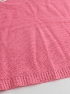 Pink knitted long sleeve sweater with round neck and ribbed hem details on white background