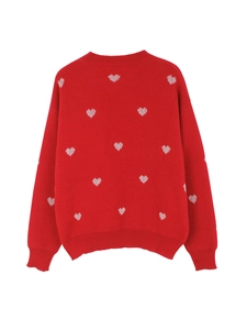 Detail of red knit sweater with white heart patterns and ribbed crewneck design