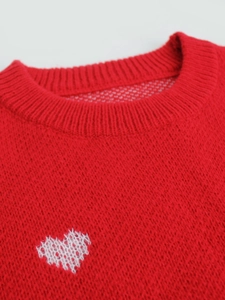 Close-up of red ribbed knit sweater with white woven heart pattern and round neckline