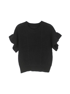 Detail of black knit top showing the textured vertical ribbing and layered ruffle sleeves