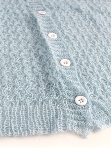 Nahaufnahme hellblaue Strickjacke mit Lochmuster, flauschiger Textur und weißen Knöpfen