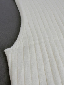 Close-up of white ribbed knit sleeveless dress showing detailed vertical texture and fabric
