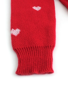 Detail of red knitted ribbed cuff with white heart pattern for women's sweater