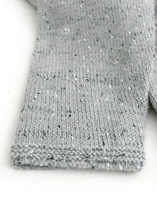 Close-up of a grey knitted sweater dress featuring premium marled texture and ribbed cuffs